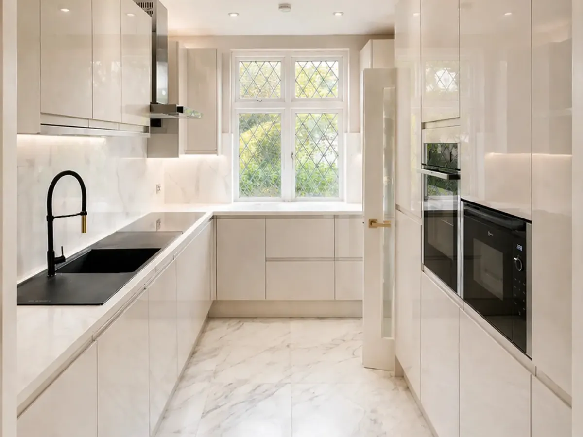 White galley kitchen renovation in Buckinghamshire with bespoke cabinetry, integrated appliances, and marble-effect flooring
